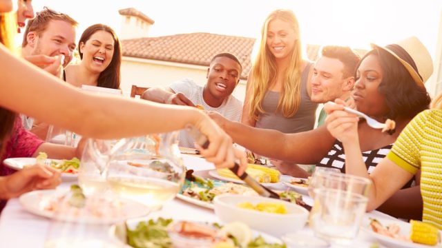 multiracial group of 20 or 30 something friends eating together outdoors