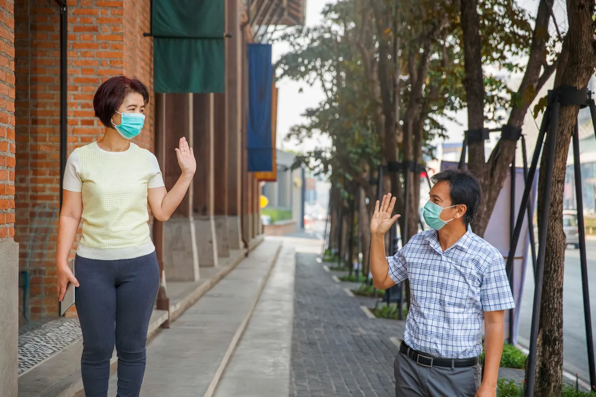 Asian middle aged people wearing mask and keep social distancing to avoid the spread of COVID-19