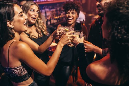 Groupe d'amis faisant la fête dans une discothèque et grillant des boissons.  Des jeunes heureux avec des cocktails au pub.