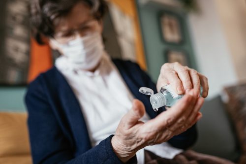 Senior woman taking care of her hand hygiene and protects herself with facial mask as her age group is mostly affected by viruses