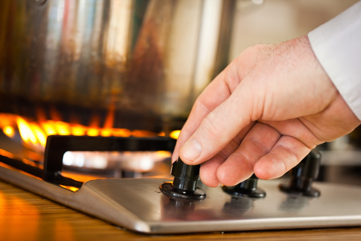 Man increasing heat on stove top to boil water