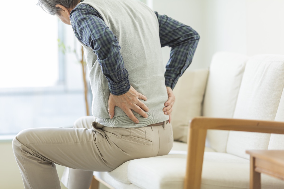 man with hip pain holding his back
