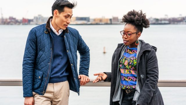 asian man and black woman talking outside by the water