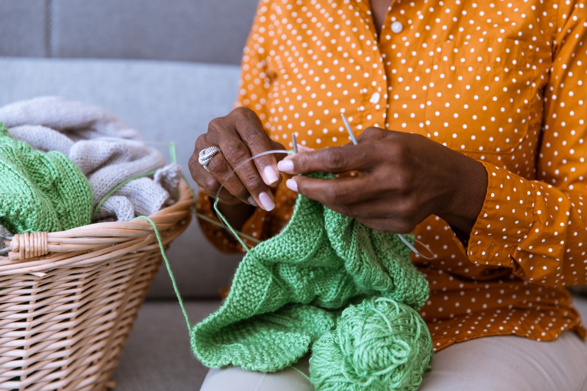 senior sitting on the couch and knitting at home