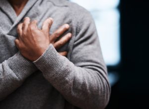 Shot of an unrecongizable man holding his chest in pain indoors