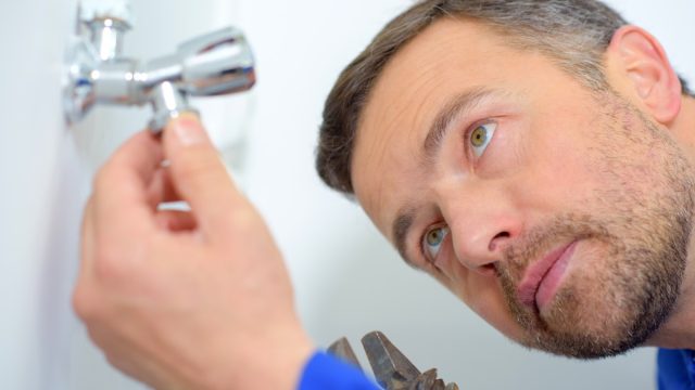 white man inspecting plumbing