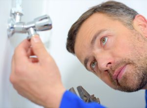 white man inspecting plumbing
