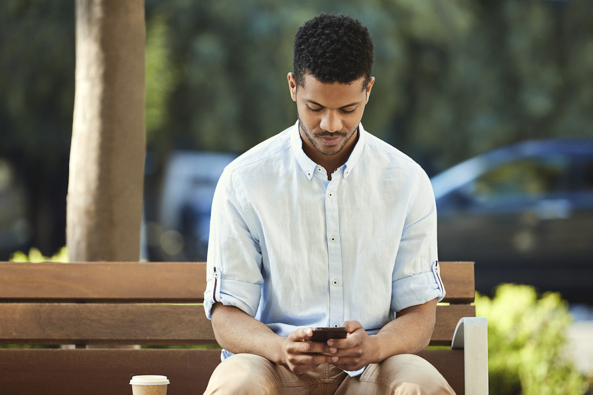 Young man using mobile phone while sitting on bench 