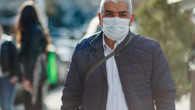 Senior Men covering his face with pollution mask for protection from viruses