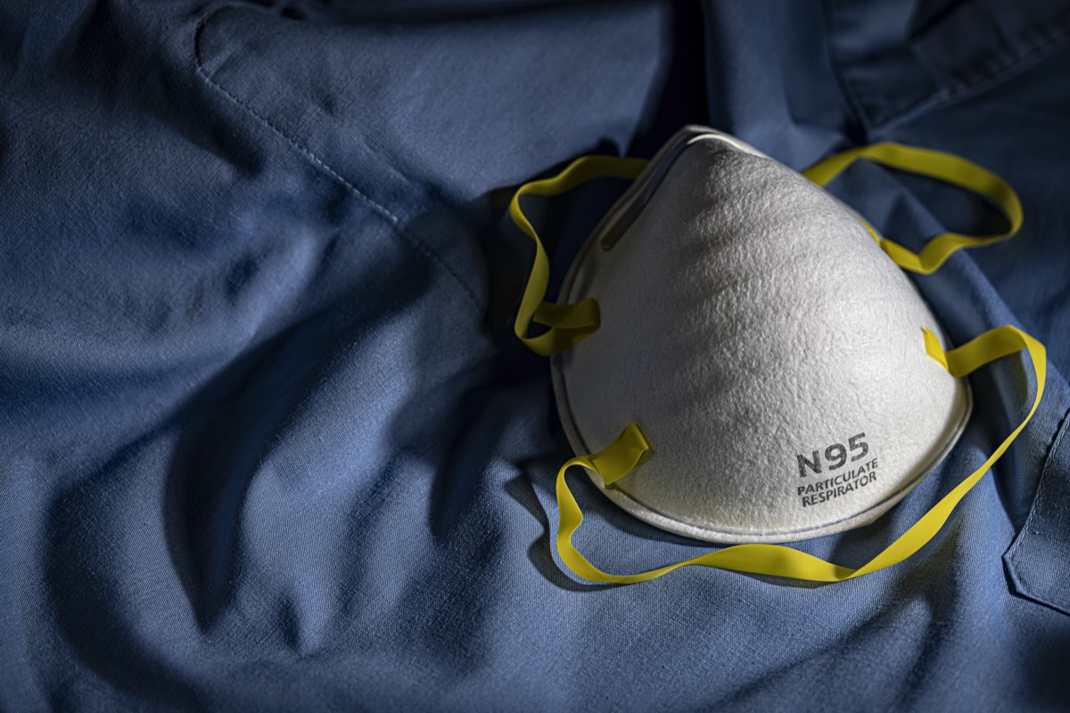 N95 PPE protective mask resting on blue medical scrubs with copy space