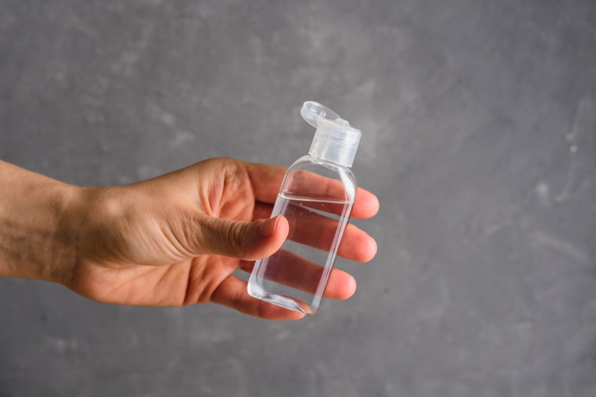 Using hand sanitizer on grey background. Personal hygiene concept