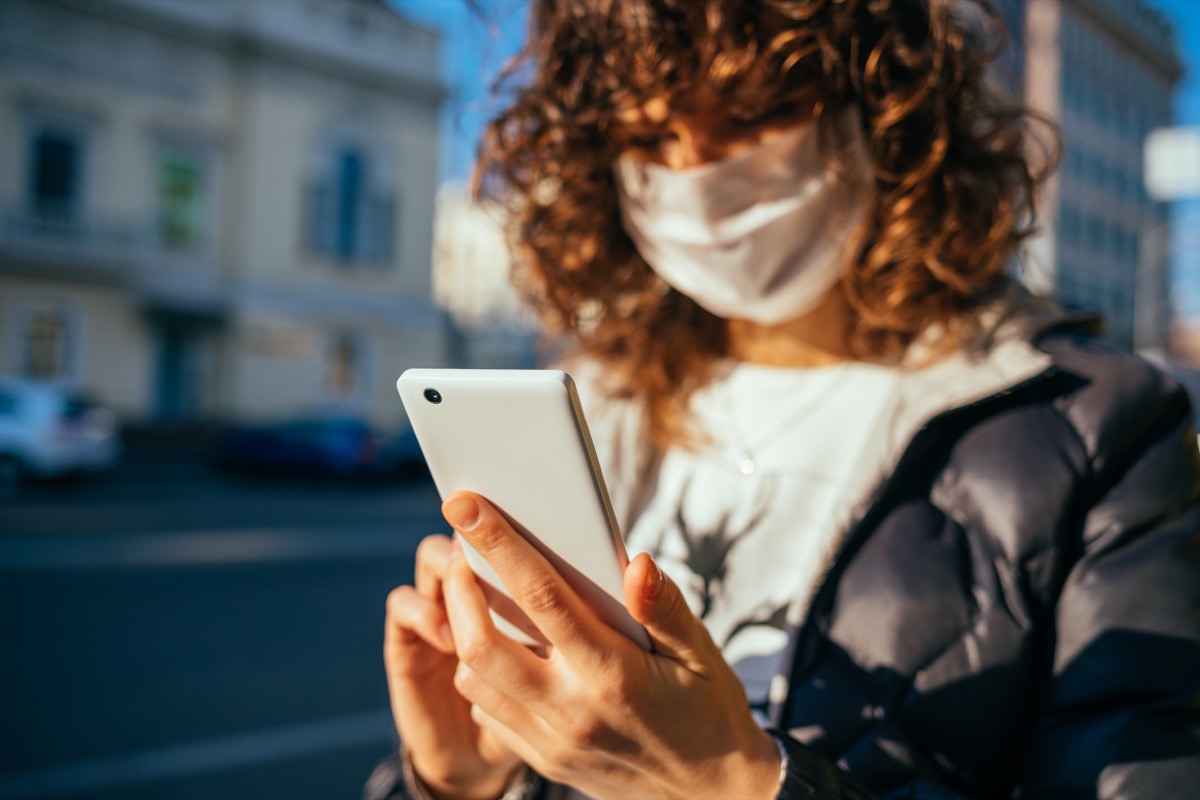 Woman using phone in public with mask on