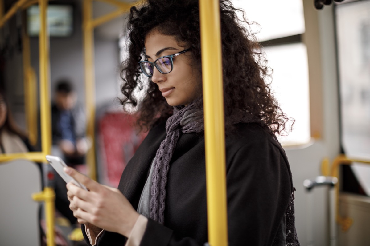Young woman traveling by bus and using smart phone