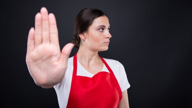 A young annoyed white female giving talk to hand gesture with palm outward