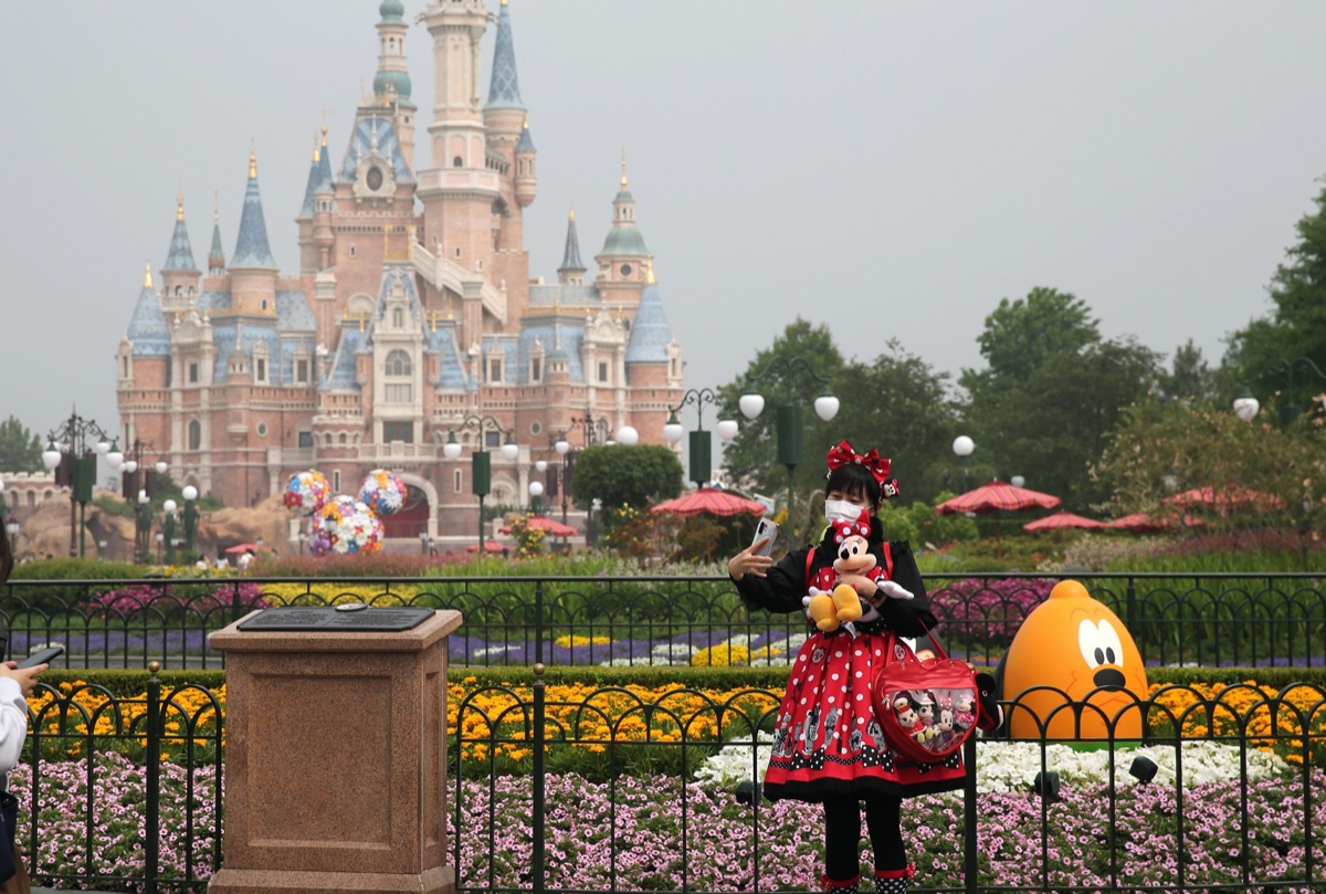 girl in disney outfit takes a selfie in front of the castle