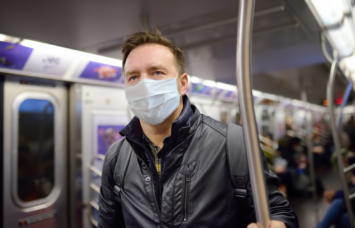 white man on subway train wearing disposable face mask