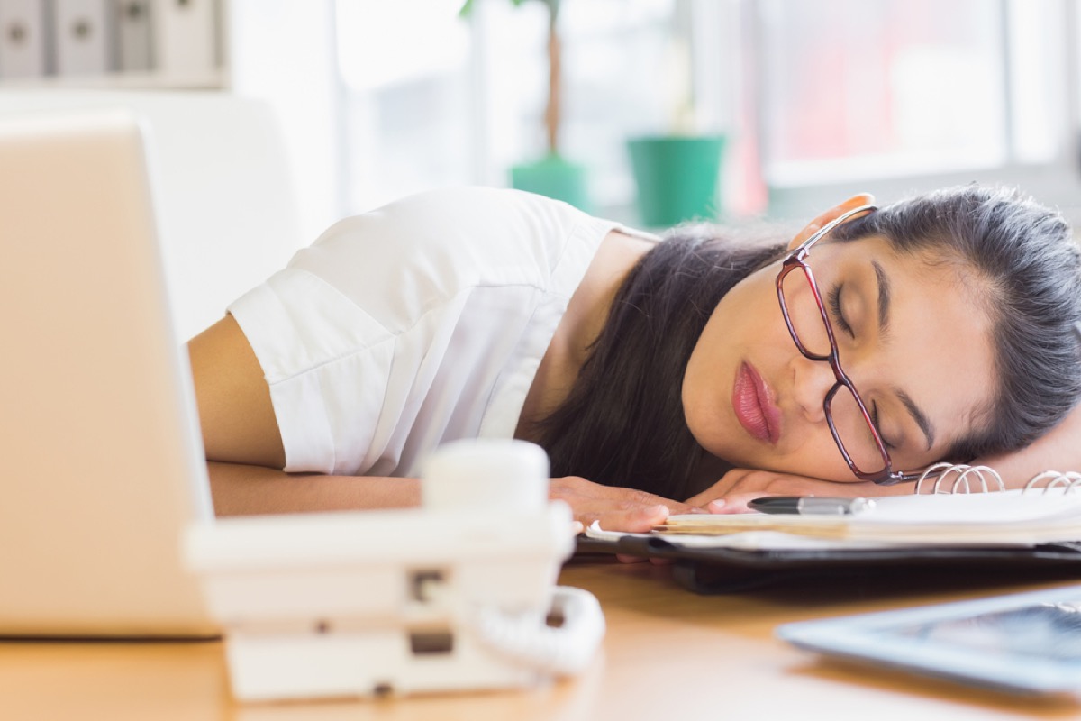 latina woman sleeping on a planner at her desk