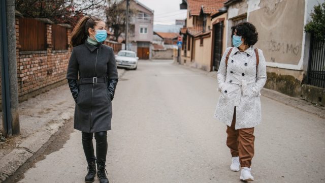 Friends walking down street socially distanced wearing masks