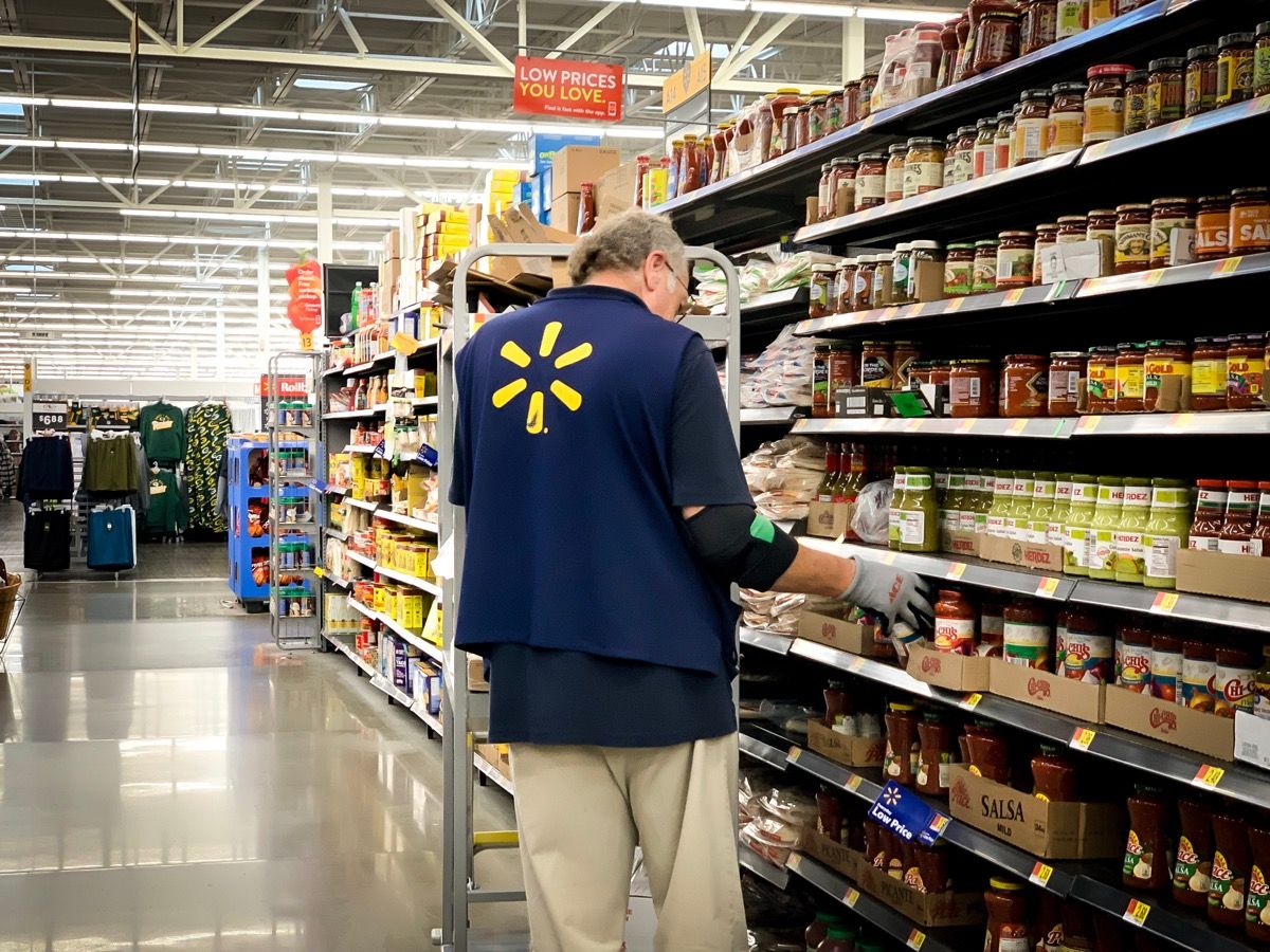 older male walmart employee stocking shelves