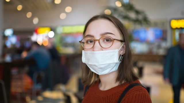 Young woman in a shopping mall wearing protective medical mask