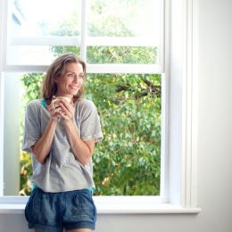 happy woman standing in front of open window