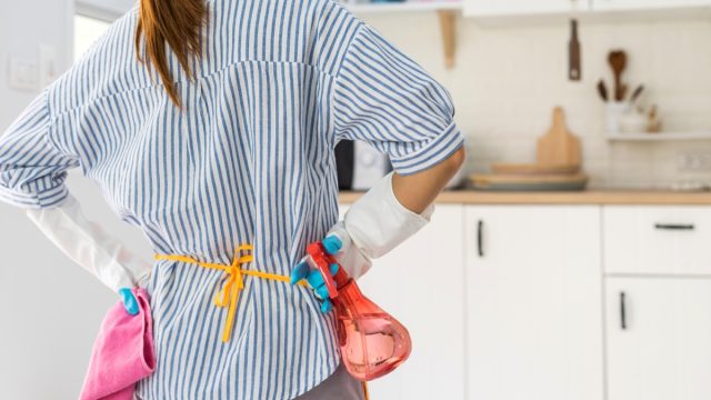 woman holding hands on hips looking at kitchen getting ready to clean her house