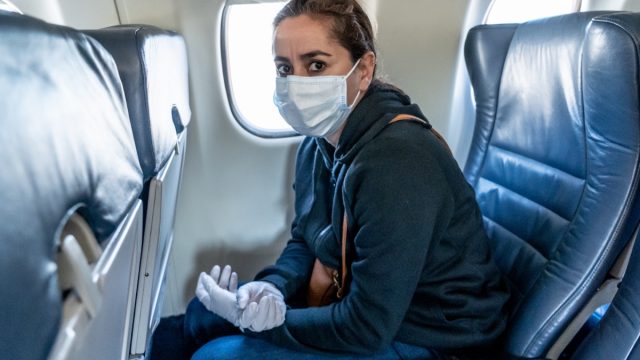 COVID-19 Pandemic border closures. Young woman on the plane returning home city after being stuck in a foreign country as governments have restricted travel to stop the coronavirus spread.