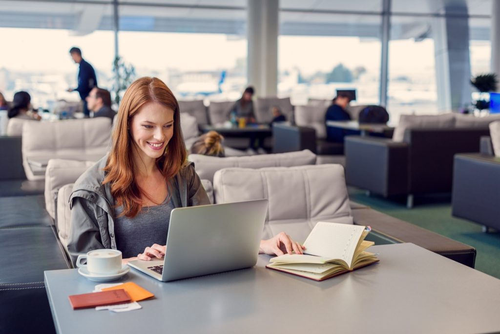 redheaded woman on laptop in airport lounge