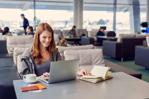 Femeie roșcată pe laptop în terminalul aeroportului