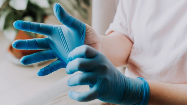 person wearing her latex surgical gloves at home before the cleaning process