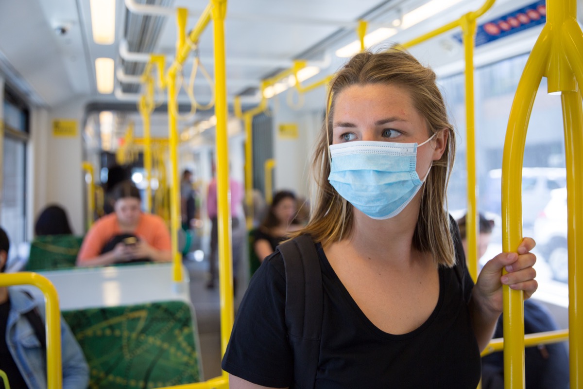 woman wearing disposable mask on public transportation during coronavirus pandemic