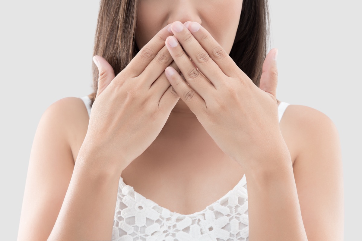 woman use both hands close mouth for not commenting or refusing on gray background
