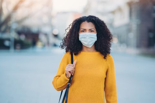 a young woman in a yellow sweater wearing a surgical mask