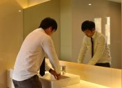 young asian man washing hands in public bathroom
