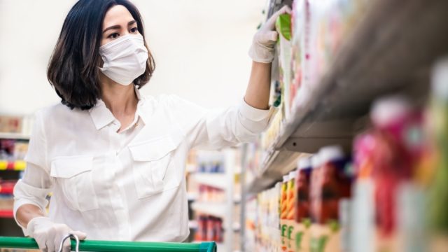 Asian woman wearing mask and gloves in grocery store