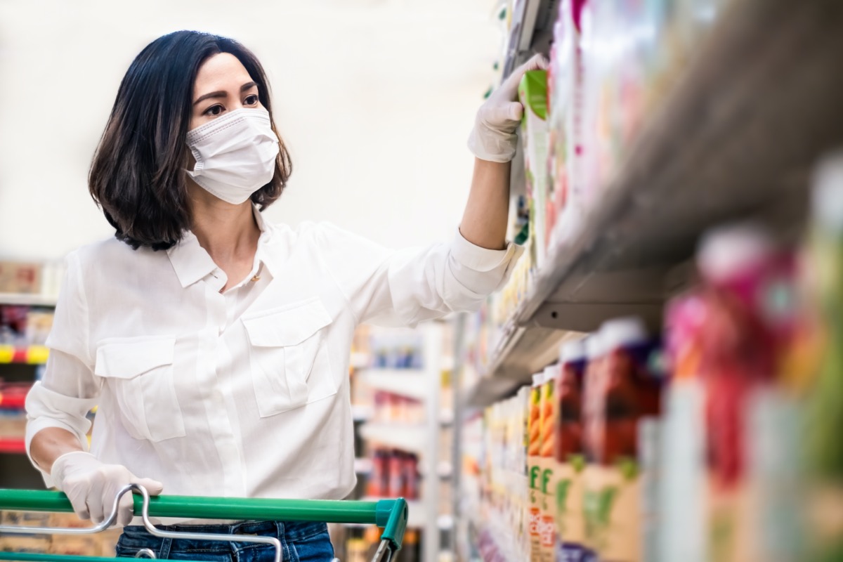 Asian woman wearing mask and gloves in grocery store