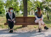 Mom and daughter social distancing on park bench