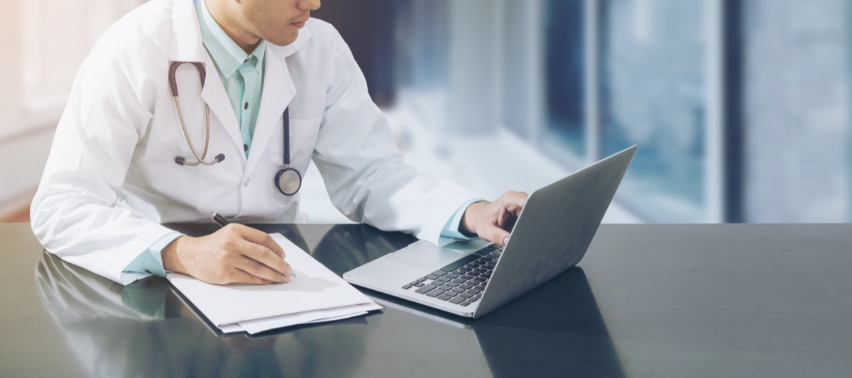 Male doctor sitting at laptop
