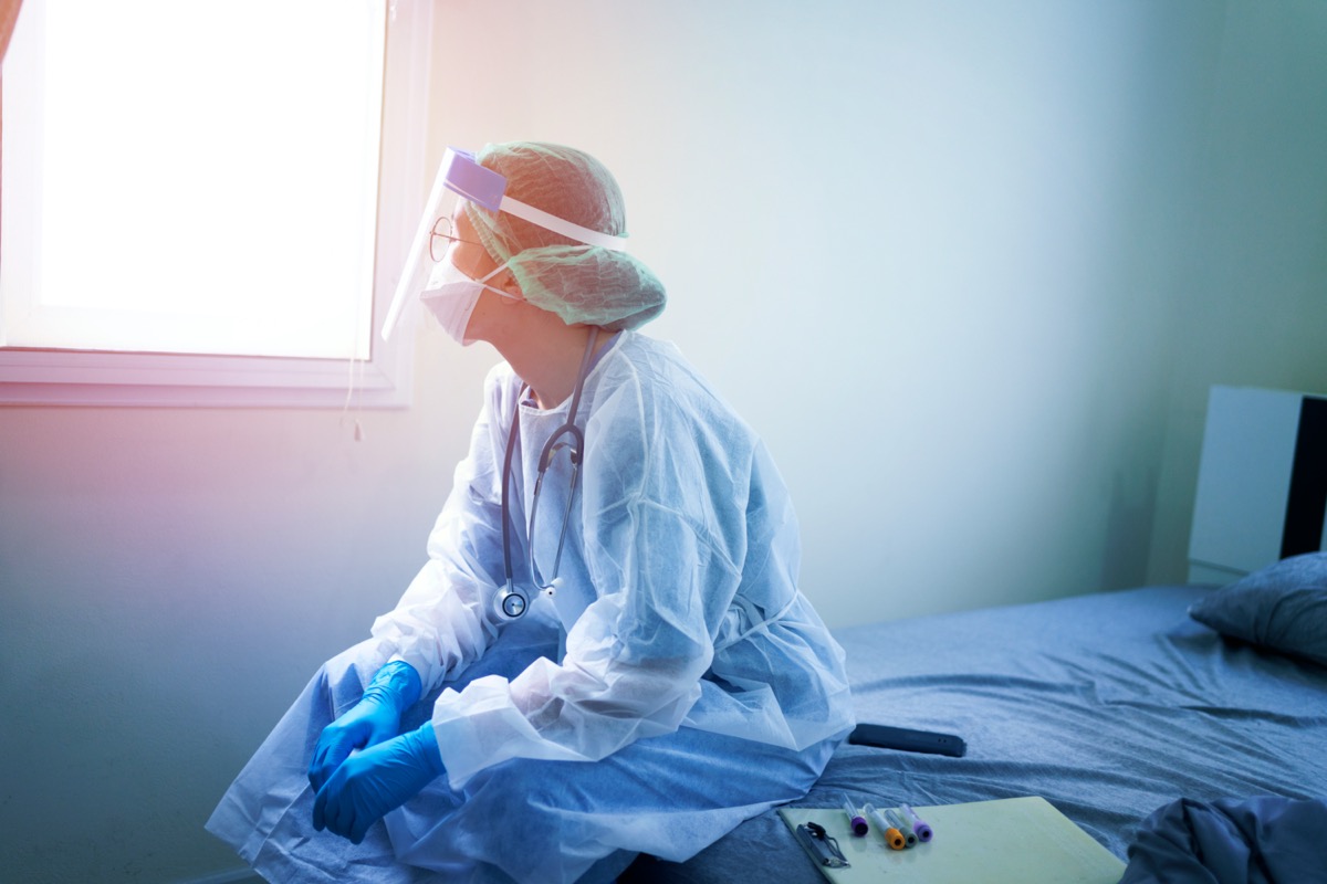 Female doctor in PPE sitting on hospital bed