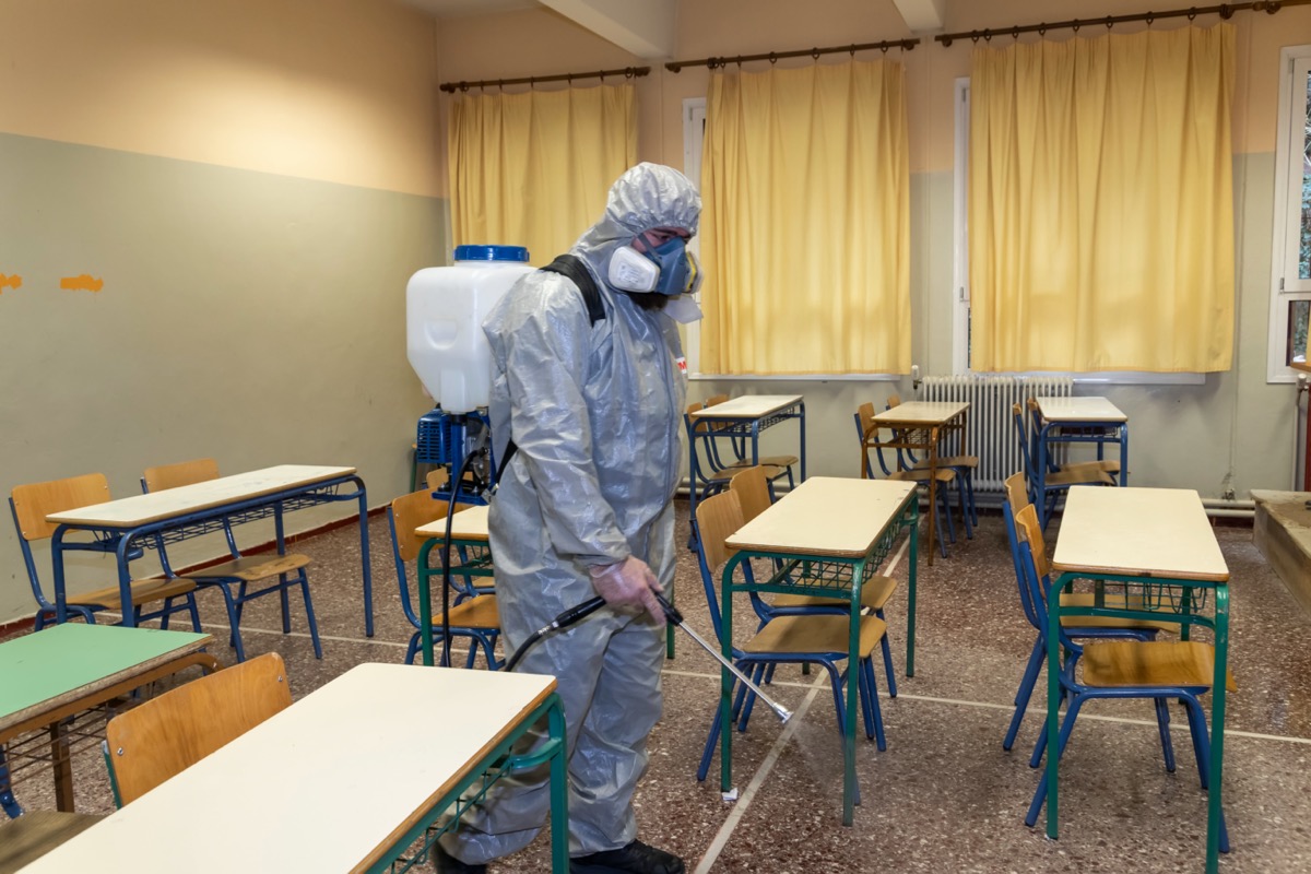 Man in hazmat suit sanitizing school classroom