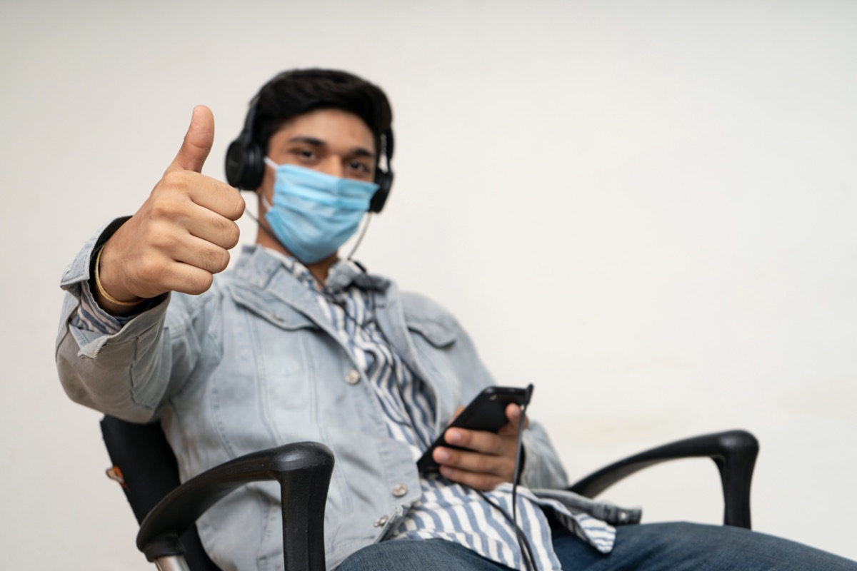 Young man wearing mask and giving thumbs up