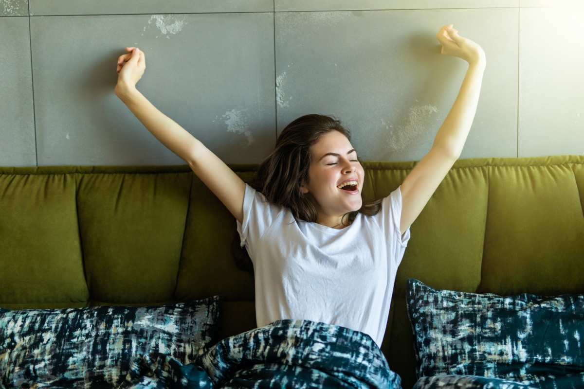 Young woman stretching in bed and smiling