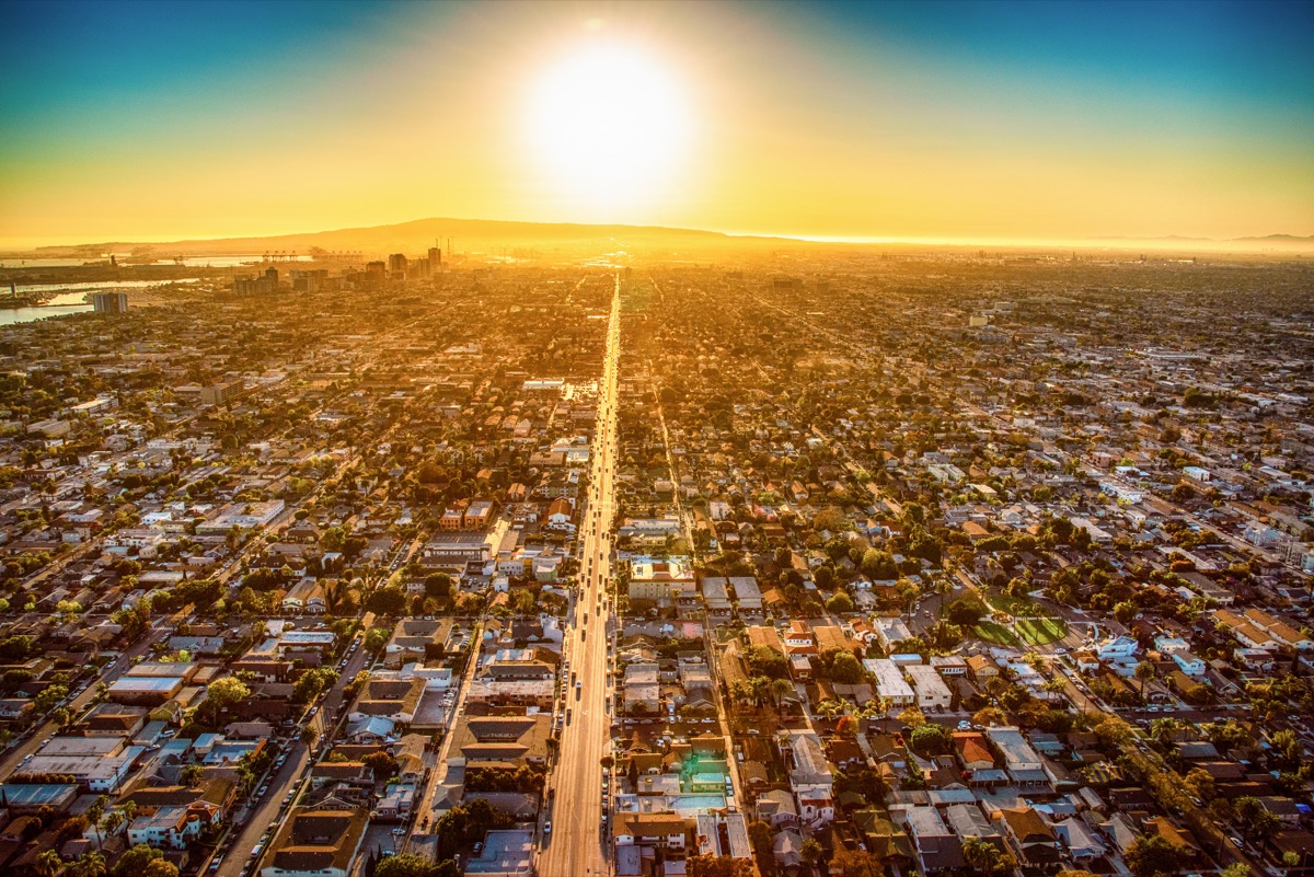 The sun nearing the horizon over Long Beach, California lining up with one of the main streets in the city illuminating the pavement shot from about 1000 feet overhead.
