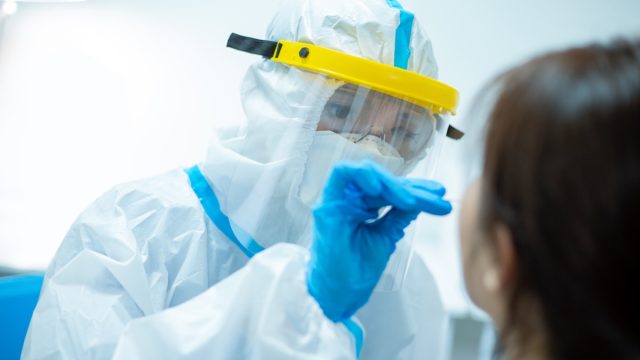 Coronavirus test - Medical worker taking a swab for corona virus sample from potentially infected woman with the isolation gown or protective suits and surgical face masks