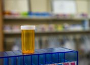 An empty prescription bottle standing on a blue case in a pharmacy
