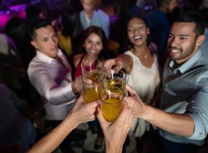 a group of multi ethnic friends makes a toast on the dance floor of a crowded nightclub