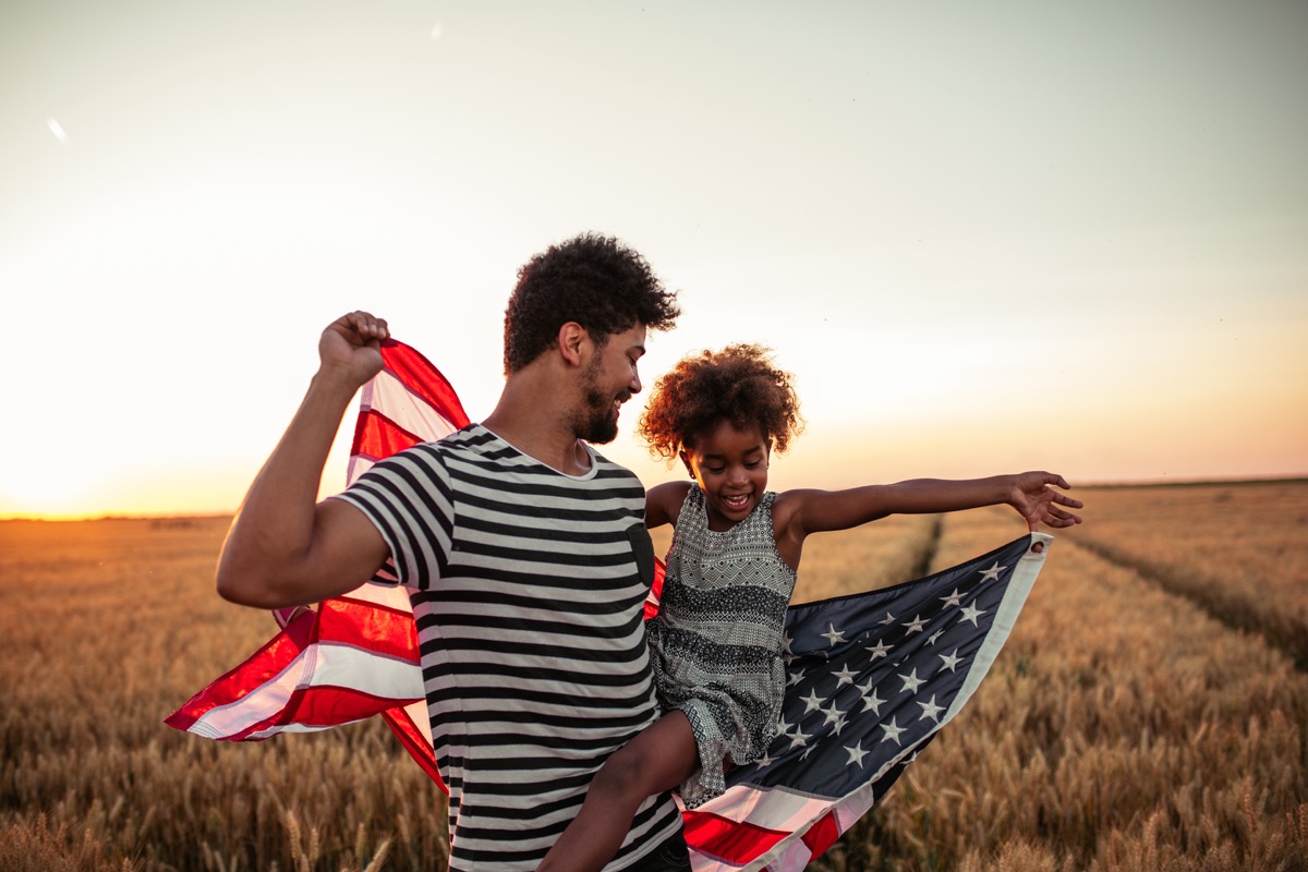 Father and daughter holding a flag for fourth of July