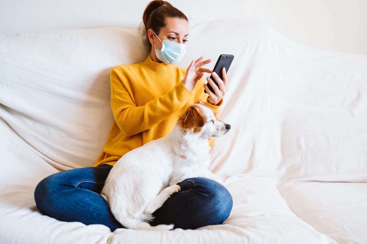 woman wearing mask with dog at home