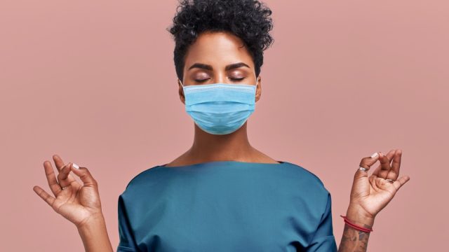 black woman meditates and breathes with a mask on