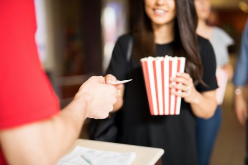 woman gives a movie ticket to a box office attendant